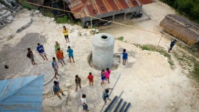 A concrete water tank and residents in a village courtyard seen from above