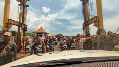 Motorcycles and passengers waiting at a ferry boarding entrance