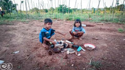 Two children playing with improvised toys on bare ground