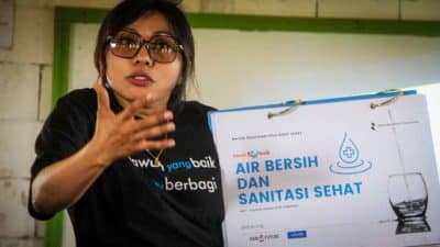 A facilitator holding a clean water and sanitation education poster