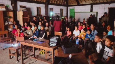Children and adults watching a projected documentary in a classroom