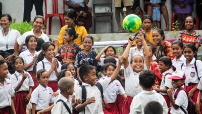 Smiling schoolchildren gathered around a football