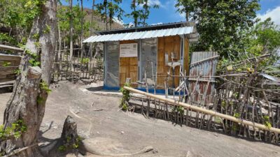 A sanitation building beside a fenced village path