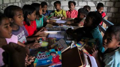 Children in a rural reading garden learning to read and write with donated educational materials.
