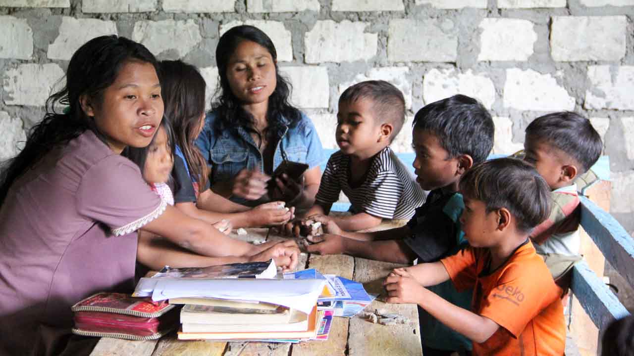 Children in a rural reading garden learning to read and write with donated educational materials.