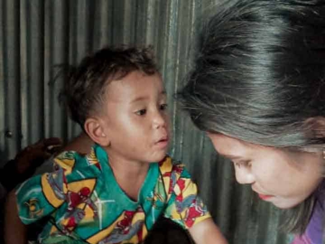 A health agent from Kawan Sehat is providing medical care to a patient in a remote village.