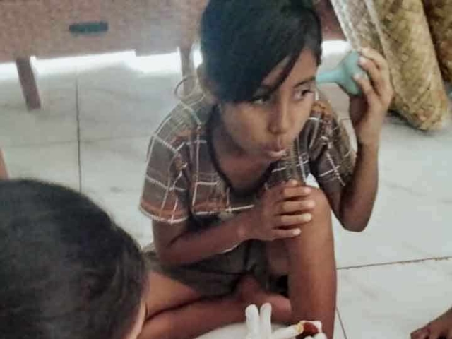 A health agent from Kawan Sehat is providing medical care to a patient in a remote village.