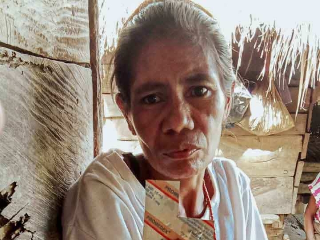 A health agent from Kawan Sehat is providing medical care to a patient in a remote village.