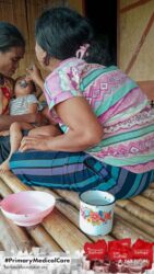 A health agent from Kawan Sehat is providing medical care to a patient in a remote village.