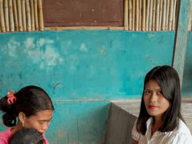 A health agent from Kawan Sehat is providing medical care to a patient in a remote village.