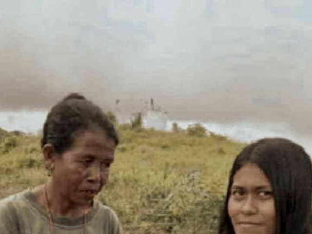 A health agent from Kawan Sehat is providing medical care to a patient in a remote village.