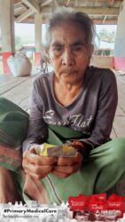 A health agent from Kawan Sehat is providing medical care to a patient in a remote village.