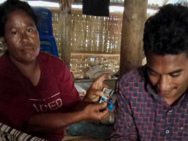 A health agent from Kawan Sehat is providing medical care to a patient in a remote village.