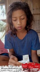 A health agent from Kawan Sehat is providing medical care to a patient in a remote village.