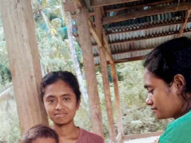 A health agent from Kawan Sehat is providing medical care to a patient in a remote village.