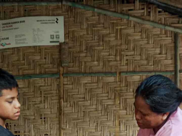 A health agent from Kawan Sehat is providing medical care to a patient in a remote village.