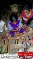 A health agent from Kawan Sehat is providing medical care to a patient in a remote village.