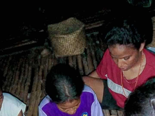 A health agent from Kawan Sehat is providing medical care to a patient in a remote village.