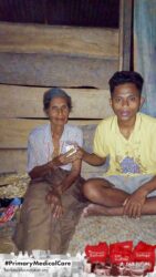 A health agent from Kawan Sehat is providing medical care to a patient in a remote village.