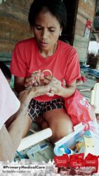 A health agent from Kawan Sehat is providing medical care to a patient in a remote village.