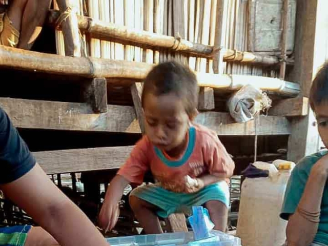 A health agent from Kawan Sehat is providing medical care to a patient in a remote village.