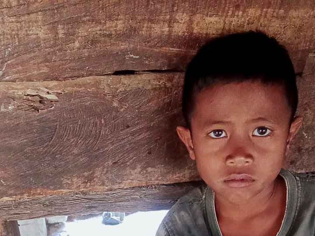 A health agent from Kawan Sehat is providing medical care to a patient in a remote village.