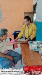 A health agent from Kawan Sehat is providing medical care to a patient in a remote village.