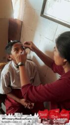 A health agent from Kawan Sehat is providing medical care to a patient in a remote village.