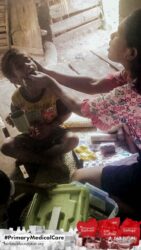 A health agent from Kawan Sehat is providing medical care to a patient in a remote village.