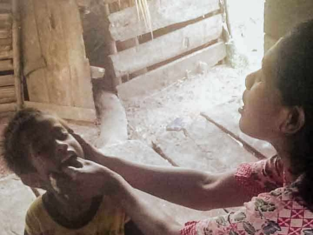 A health agent from Kawan Sehat is providing medical care to a patient in a remote village.