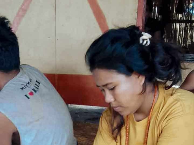 A health agent from Kawan Sehat is providing medical care to a patient in a remote village.