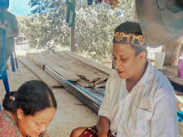 A health agent from Kawan Sehat is providing medical care to a patient in a remote village.