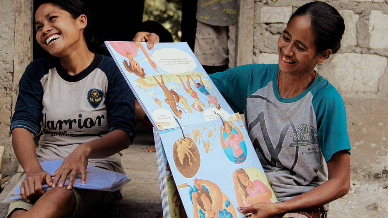 Women from rural villages reading the Kawan Sehat book and learning about healthy living.