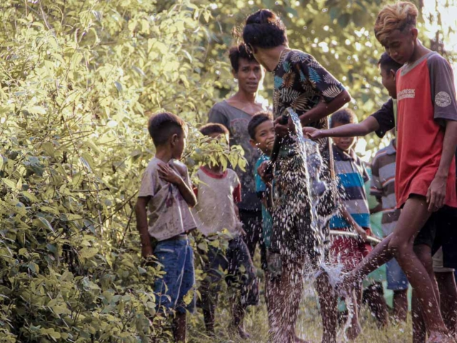 Children sitting on a reservoir in a rural village, celebrating the arrival of clean water.