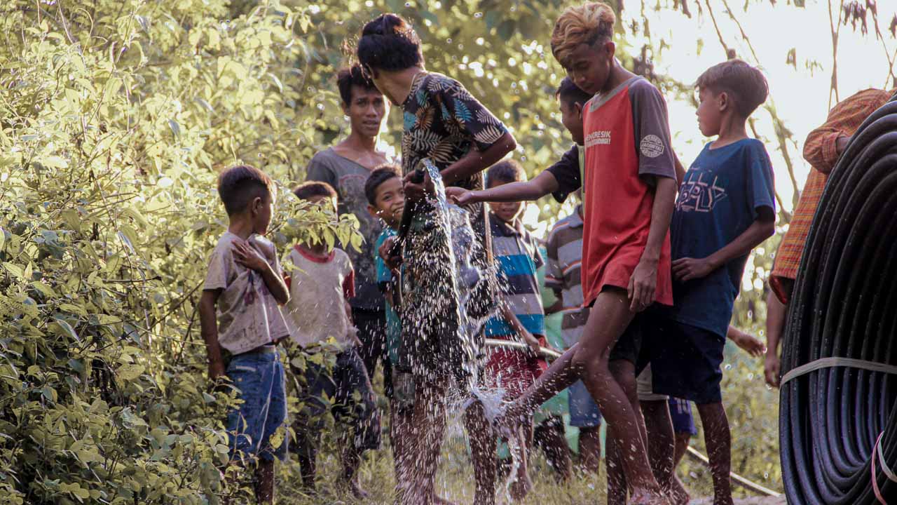 Children sitting on a reservoir in a rural village, celebrating the arrival of clean water.