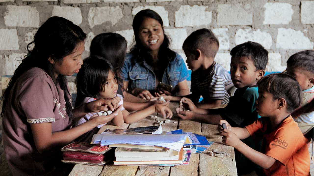 Children in a rural reading garden learning to read and write with donated educational materials.