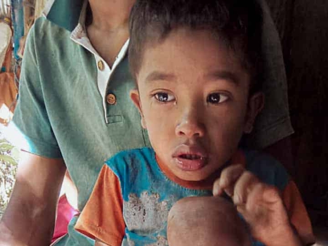 A health agent from Kawan Sehat is providing medical care to a patient in a remote village.