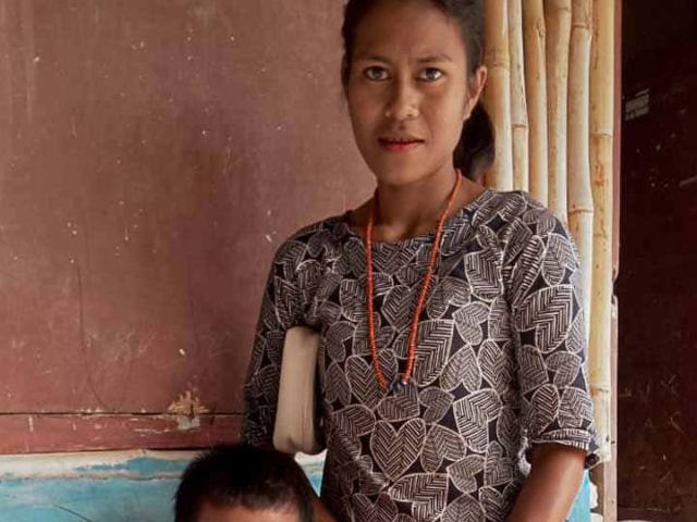 A health agent from Kawan Sehat is providing medical care to a patient in a remote village.