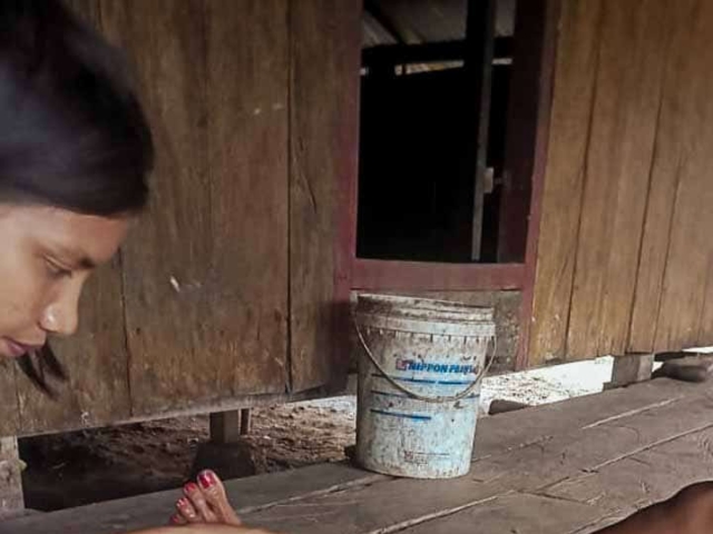 A health agent from Kawan Sehat is providing medical care to a patient in a remote village.