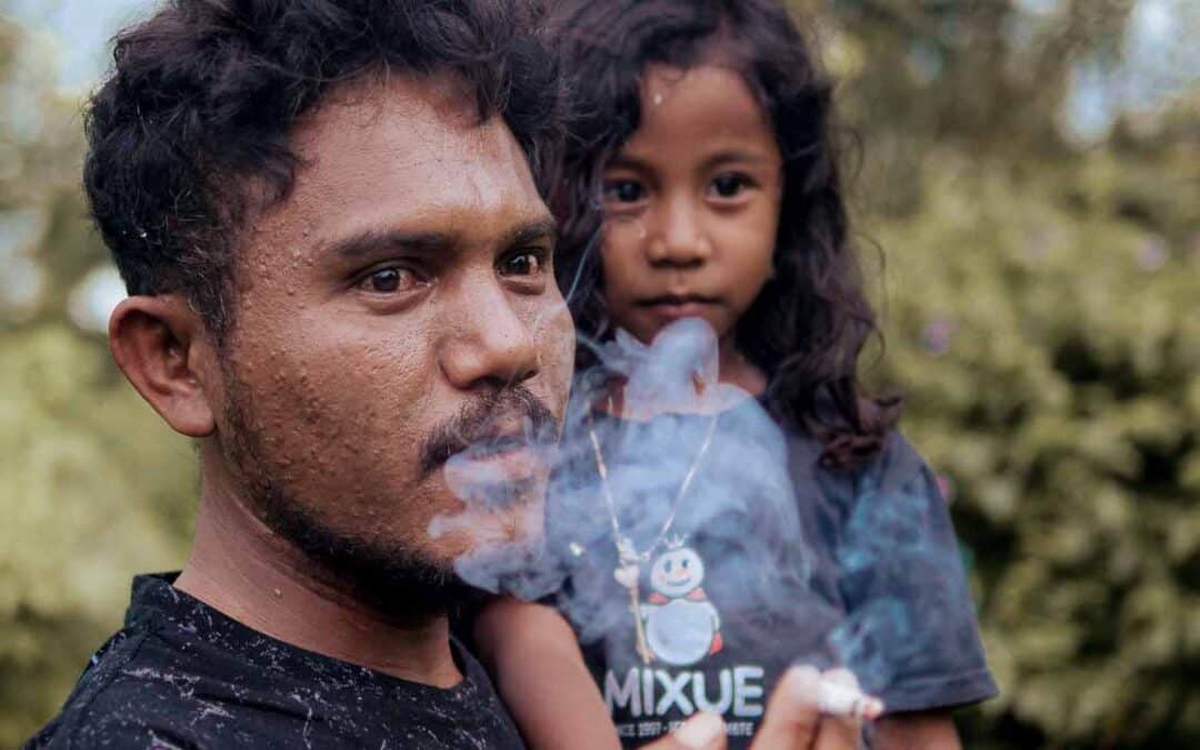 Anti-tobacco poster displayed in an Indonesian village, educating families about passive smoke dangers.