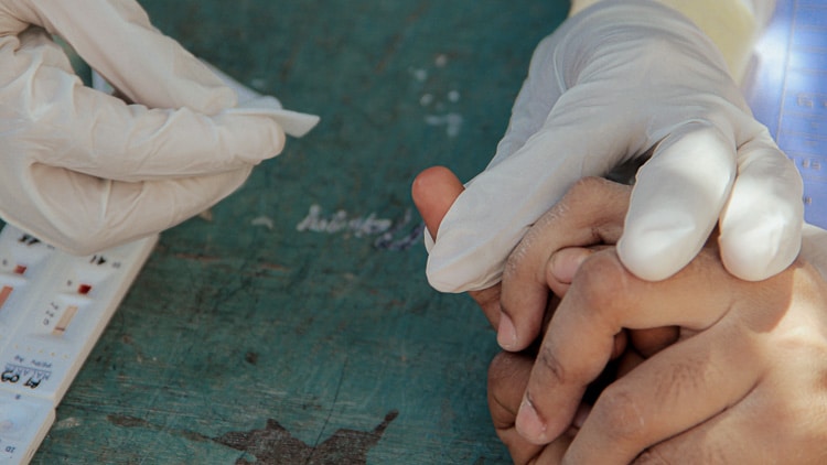 Un agent de santé effectuant un test de dépistage du paludisme à la main dans un village rural isolé