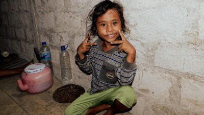 Children carrying water containers on foot in rural Indonesia, facing tough living conditions without access to clean water