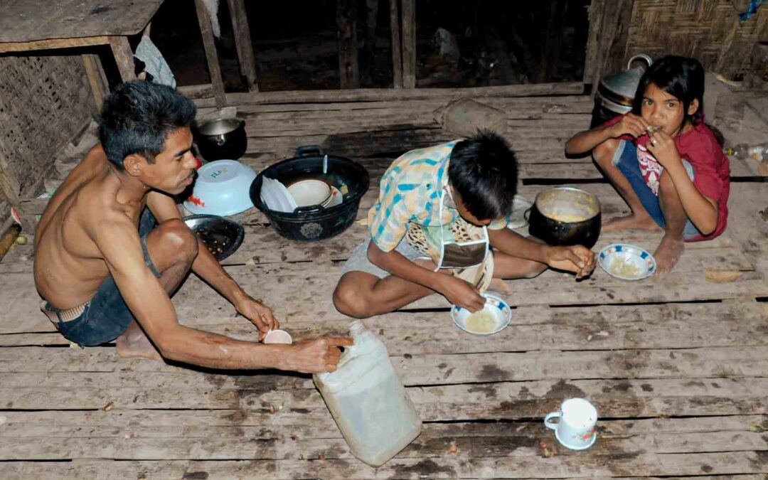 Children in rural Indonesia carrying water containers through dry, dusty paths to their home