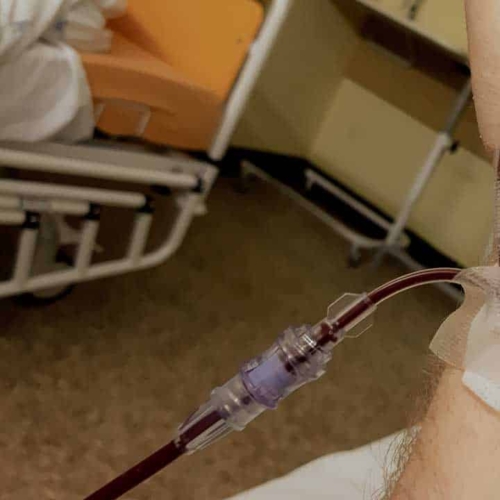 Close-up of a patient&#039;s hand receiving a blood transfusion through an IV line