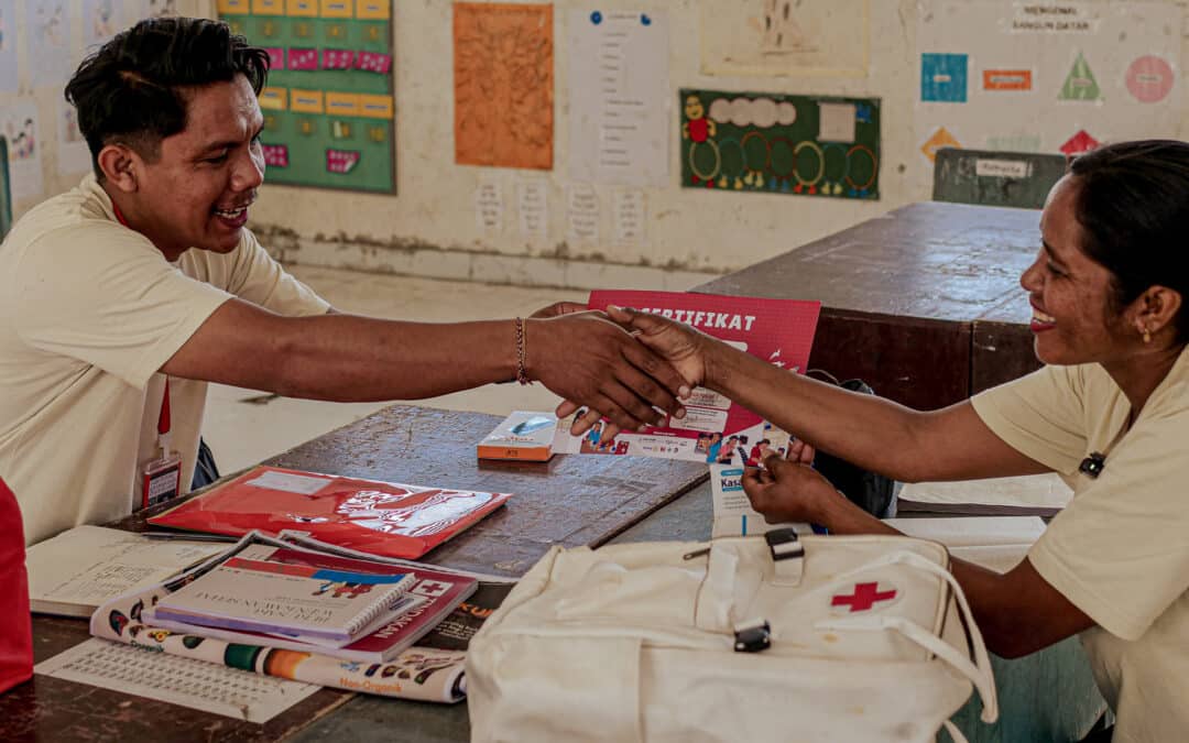 A health coordinator gives a certificate to a rural health agent while checking her medicine supply in Laindatang village