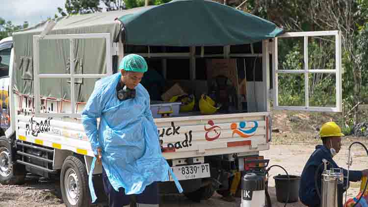 A Kawan Sehat health worker puts on his protective gear before carrying out indoor insecticide spraying to combat malaria, with support from the Fair Future logistics vehicle.