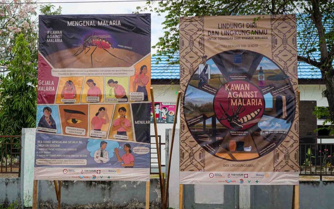 Two large malaria prevention billboards in Indonesian showing symptoms, transmission, and protection methods as part of the Kawan Against Malaria campaign