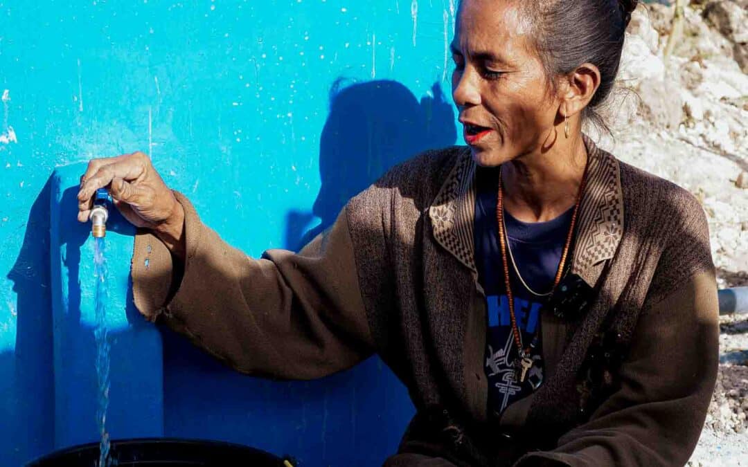Hambarta woman opening a tap connected to a new ferrocement rainwater tank, part of Fair Future’s clean water project.