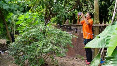 Volunteer taking photos to assess malaria risk factors around a house in Umalulu.