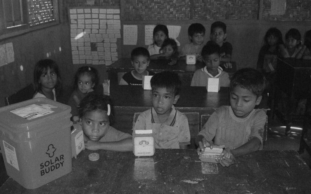 Teacher shows children how to use a SolarBuddy lamp at Matawai Pandangu